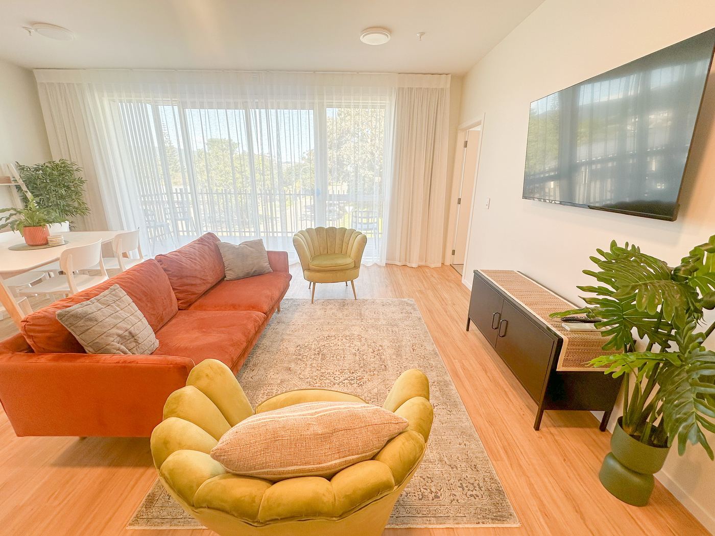 Living room with sofa, armchair, TV and sheer balcony curtains